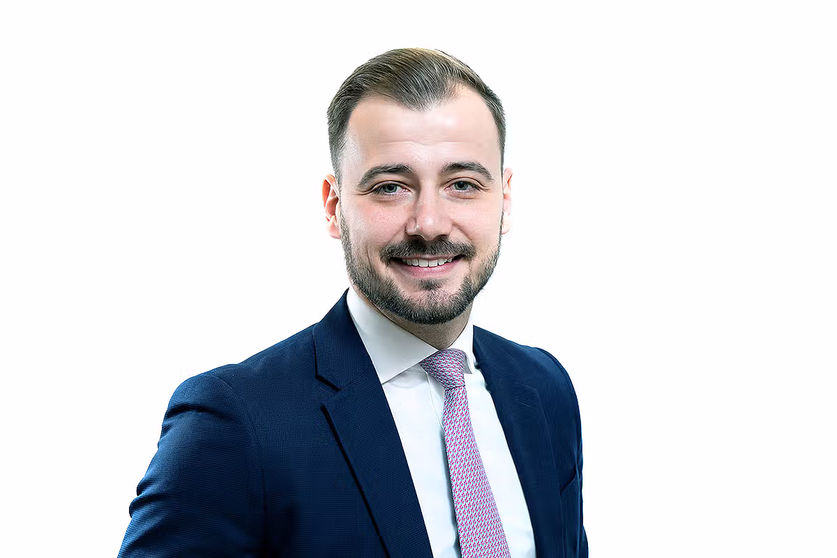 Business headshot of a professional in a blue suit and pink tie on a white background