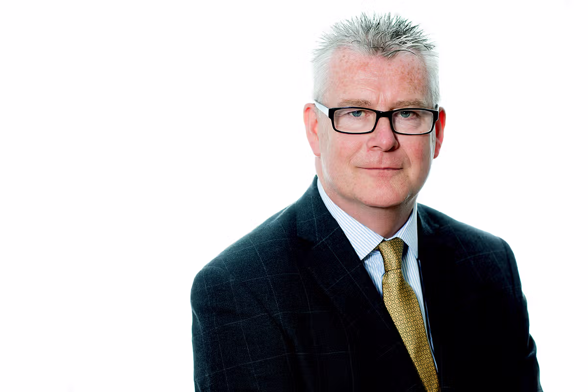 Executive headshot of a professional wearing glasses and a yellow tie on a white background