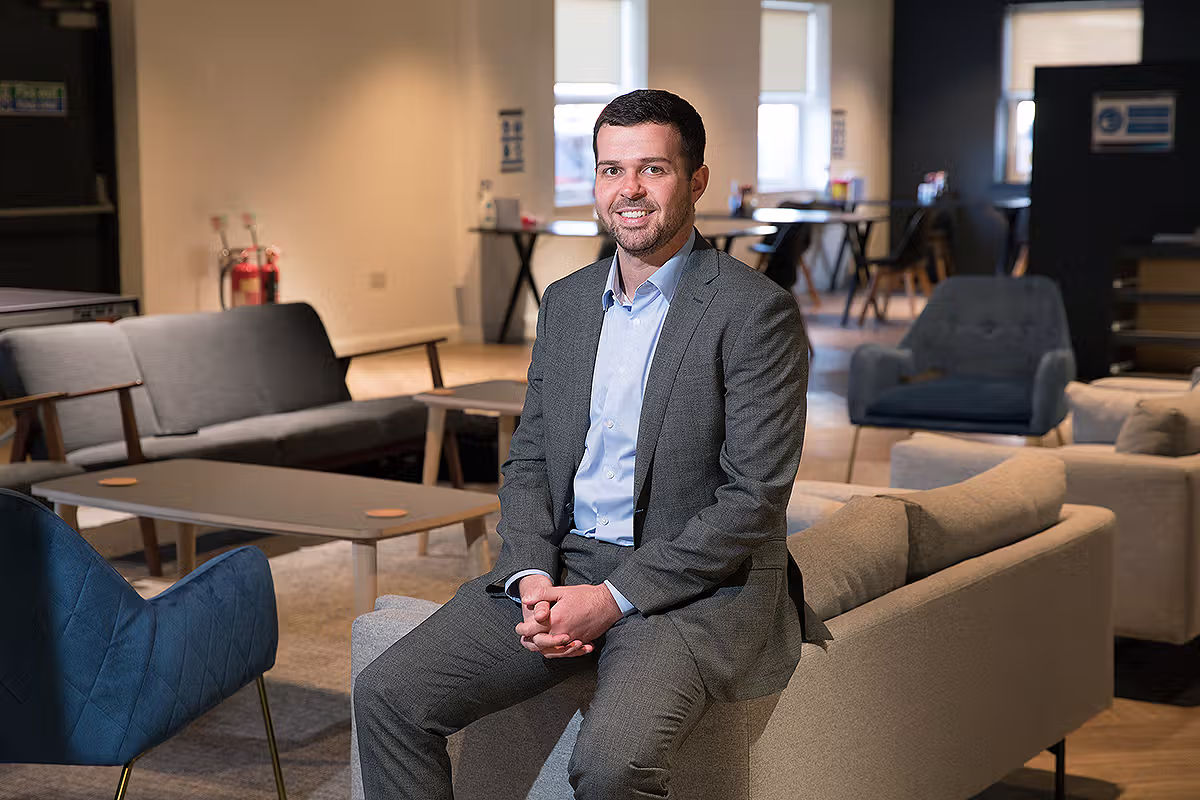 Corporate portrait of a business professional seated in a modern office lounge environment