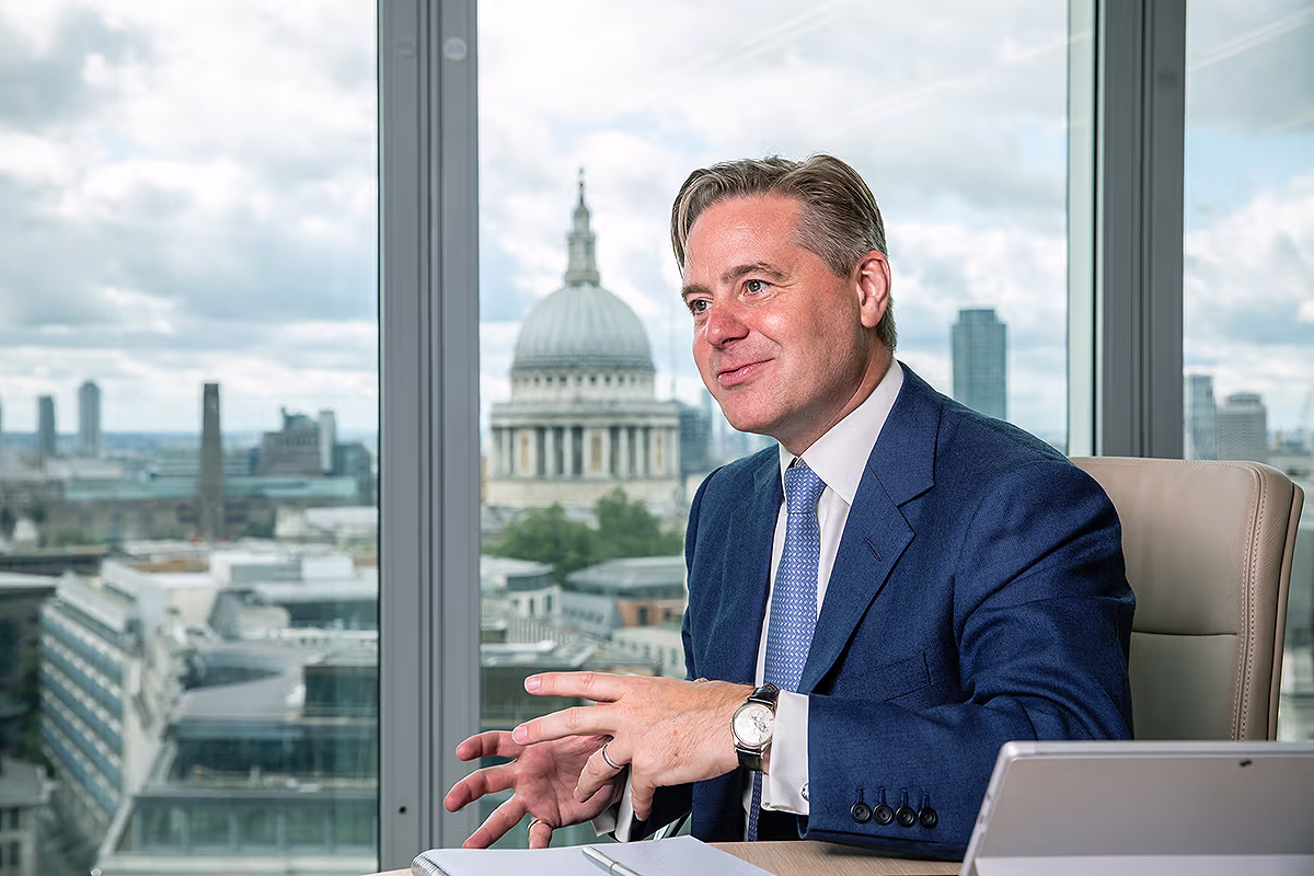 Schroders Personal Wealth London CEO Mark Duckworth seated in the office at 1 London Wall Place with St Paul's Cathedral behind him