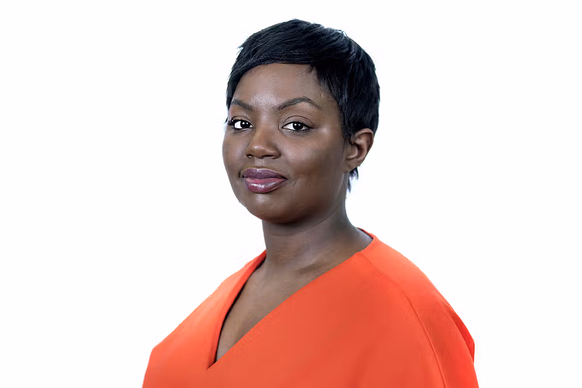 Professional portrait of a woman in an orange dress against a light studio background