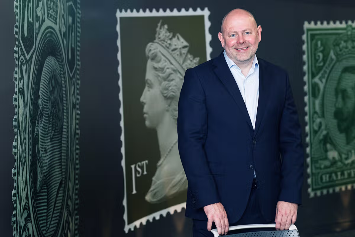 Corporate event portrait of a speaker standing beside branded display panels