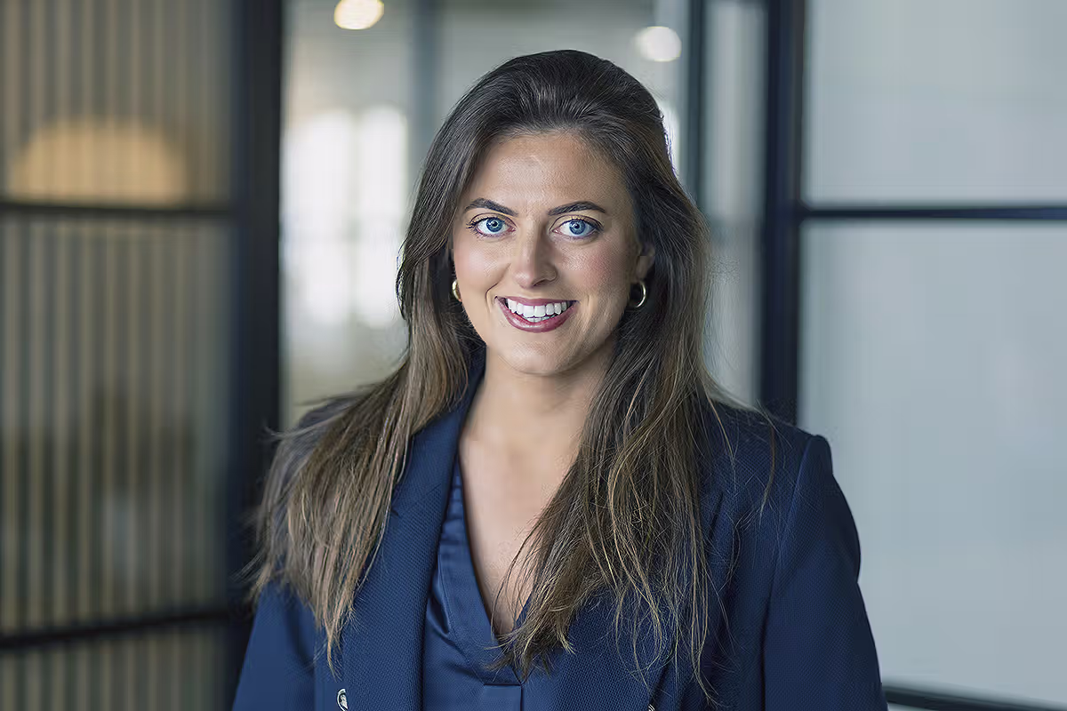 Professional portrait of a woman in a blue blazer inside a modern office