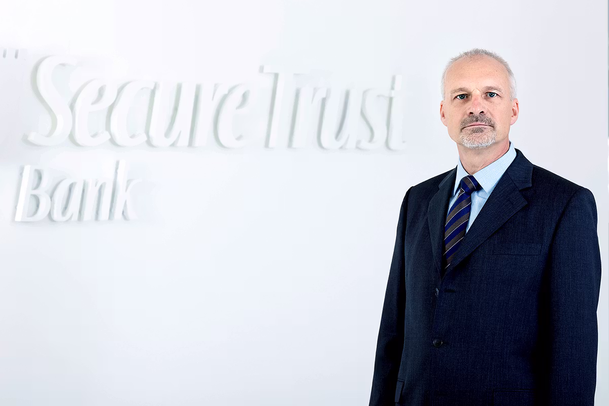 Corporate portrait of a businessman in front of Secure Trust Bank branding