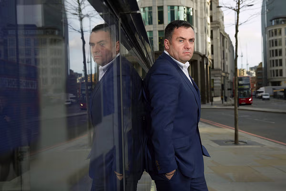 Executive portrait of a businessman beside a reflective glass wall in the City of London