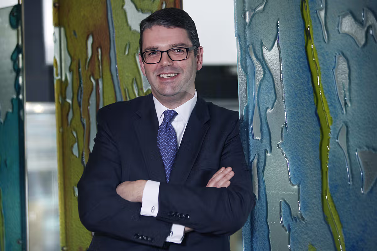 Executive portrait of a businessman in a suit standing between textured decorative panels