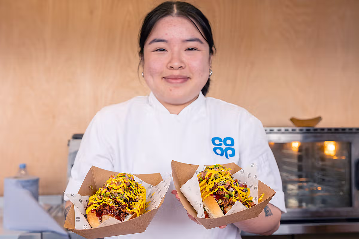 Co-op Food Festival PR photography showing a chef holding branded hot dogs during a London food activation at Potters Fields Park