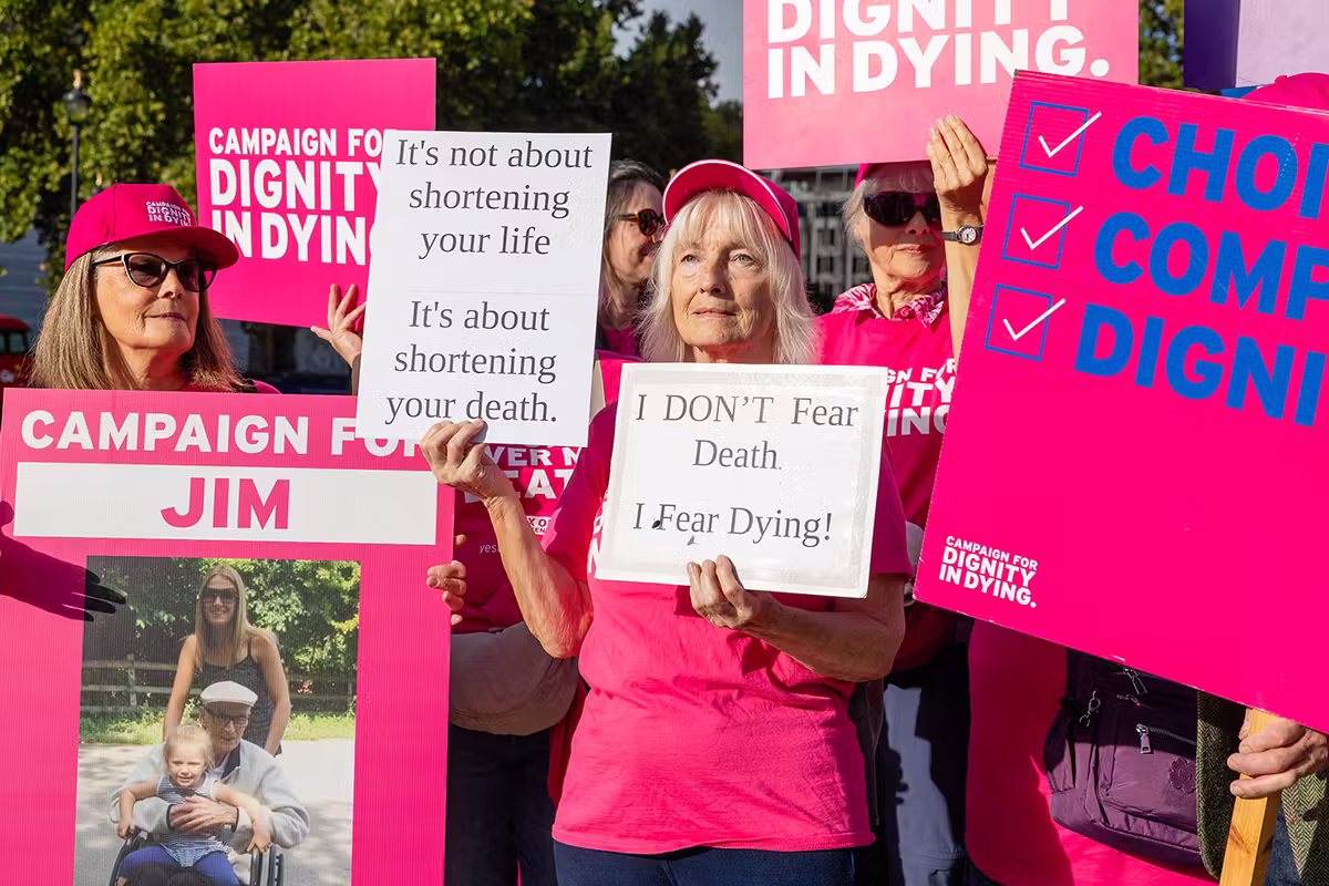 Dignity in Dying campaign supporters in bright pink campaign clothing holding placards with personal messages at a Westminster public affairs event